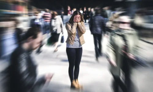 Panic attack in public place. Woman having panic disorder in city. Psychology, solitude, fear or mental health problems concept. Depressed sad person surrounded by people walking in busy street.