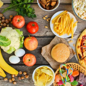 Fastfood and healthy food on old wooden background. Concept choosing correct nutrition or of junk eating. Top view.